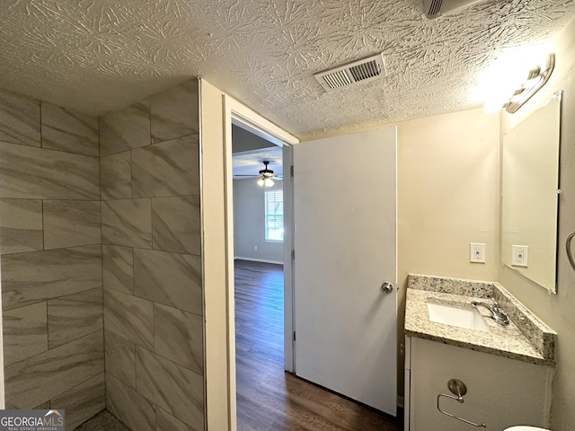 bathroom featuring ceiling fan, vanity, a textured ceiling, and hardwood / wood-style flooring