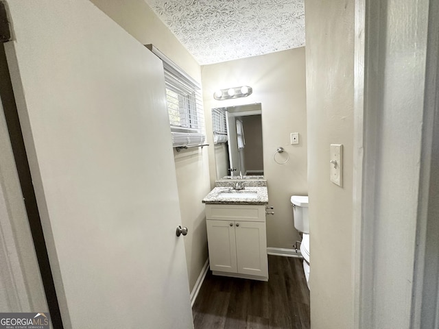 bathroom with toilet, vanity, a textured ceiling, and hardwood / wood-style flooring