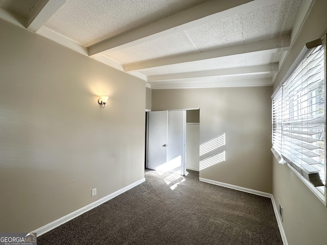 spare room with carpet, beamed ceiling, and a textured ceiling