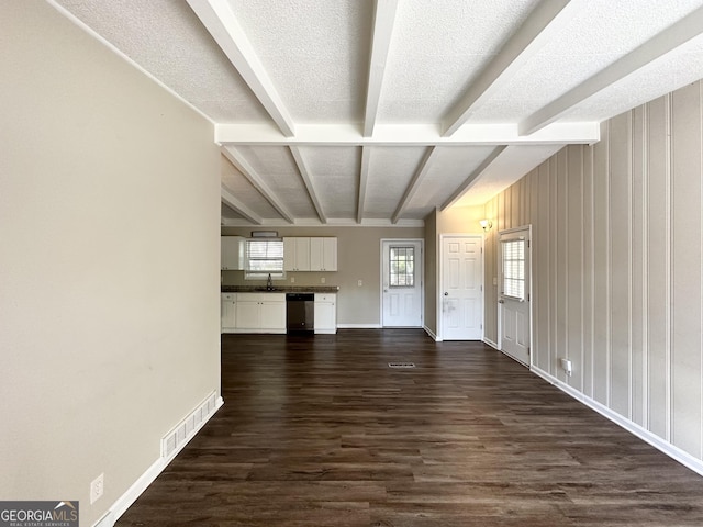 unfurnished living room featuring beam ceiling, sink, a textured ceiling, and dark hardwood / wood-style floors