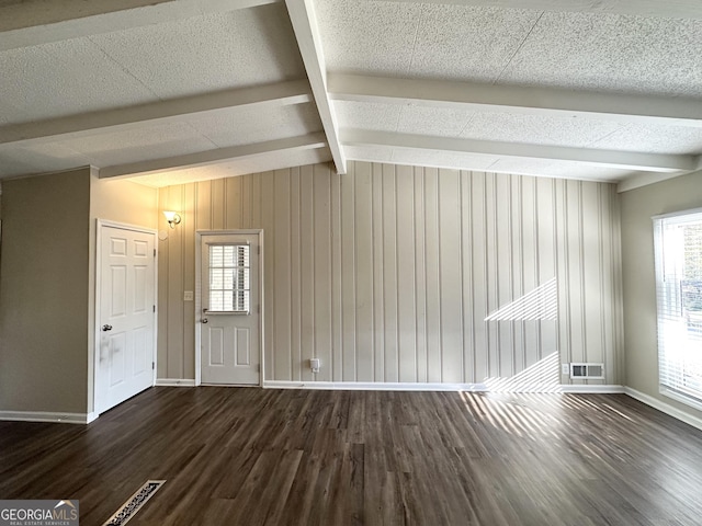 spare room with lofted ceiling with beams, wooden walls, and dark wood-type flooring