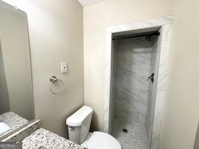 bathroom with vanity, toilet, and a tile shower