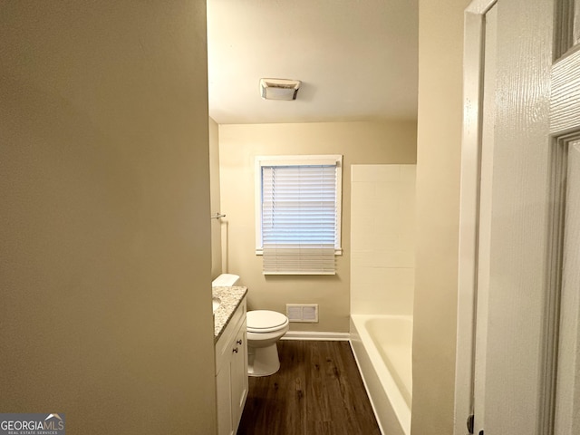 bathroom with a tub to relax in, vanity, hardwood / wood-style flooring, and toilet