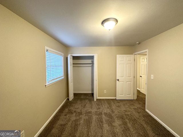 unfurnished bedroom featuring a closet and dark carpet