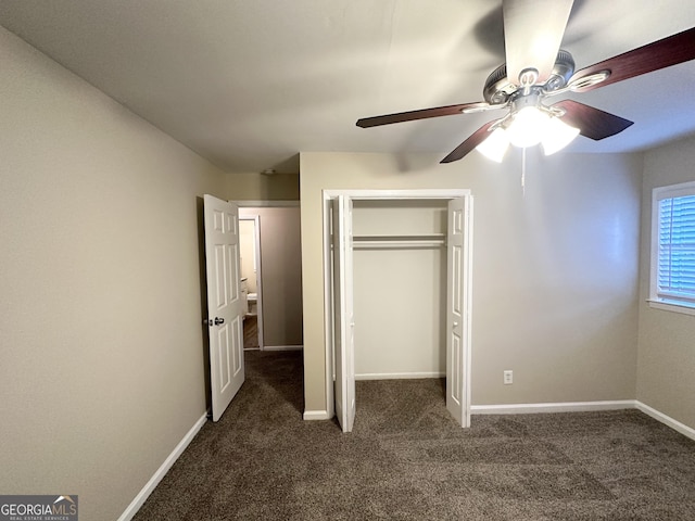 unfurnished bedroom with ceiling fan, dark carpet, and a closet