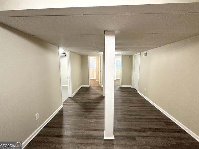 interior space featuring a drop ceiling and dark wood-type flooring