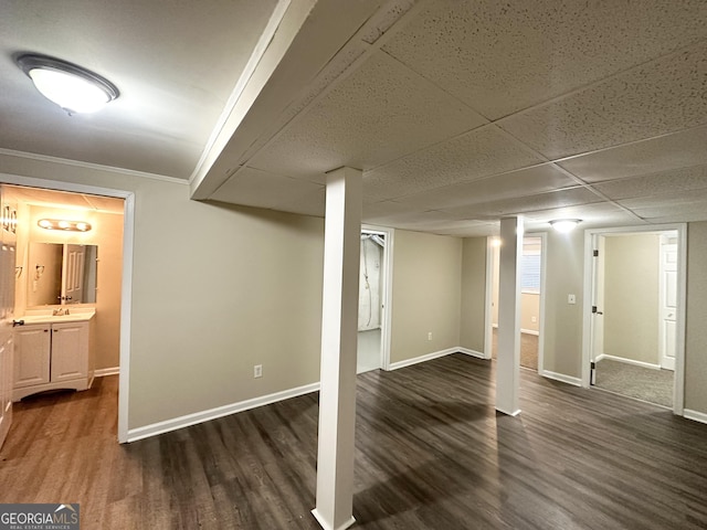 basement with dark hardwood / wood-style flooring, crown molding, and sink