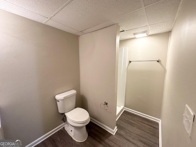 bathroom featuring a shower, a paneled ceiling, hardwood / wood-style flooring, and toilet