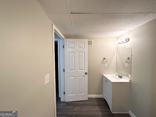 bathroom with a paneled ceiling, vanity, and wood-type flooring