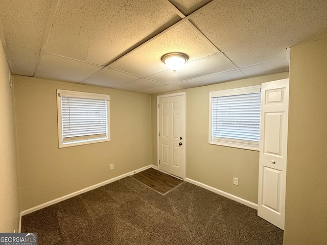 empty room featuring a drop ceiling and dark carpet