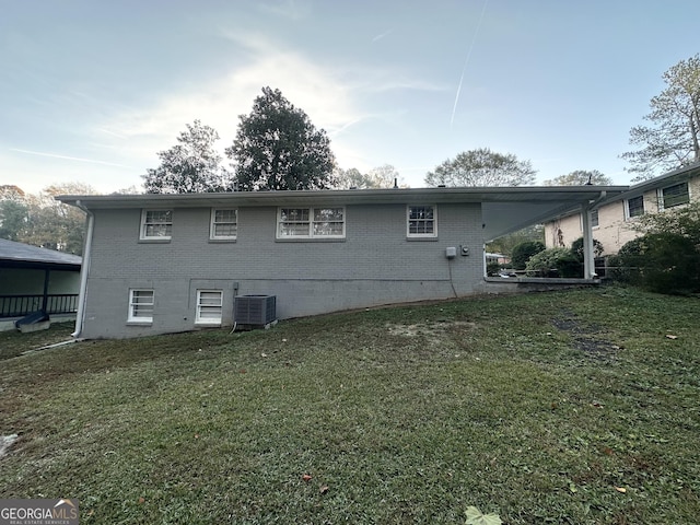 back of property with a yard and central AC