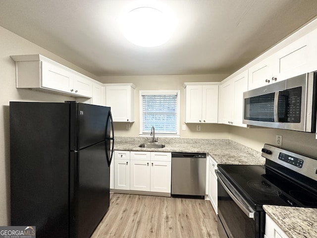 kitchen with white cabinets, sink, light hardwood / wood-style flooring, appliances with stainless steel finishes, and light stone counters