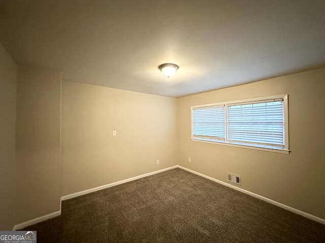 unfurnished room featuring dark carpet