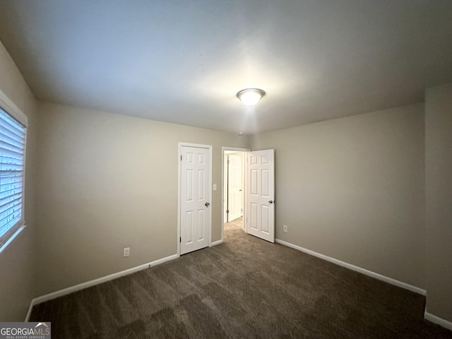 unfurnished bedroom with dark colored carpet