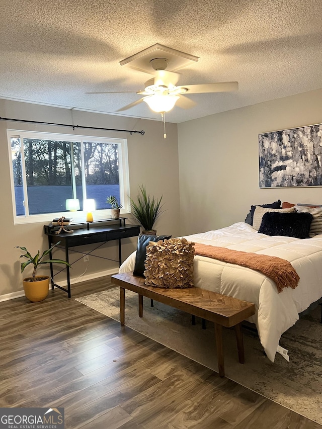 bedroom featuring dark hardwood / wood-style flooring, ceiling fan, and a textured ceiling