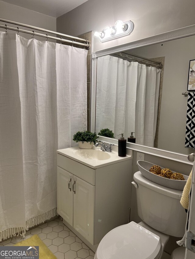 bathroom featuring vanity, curtained shower, tile patterned floors, and toilet