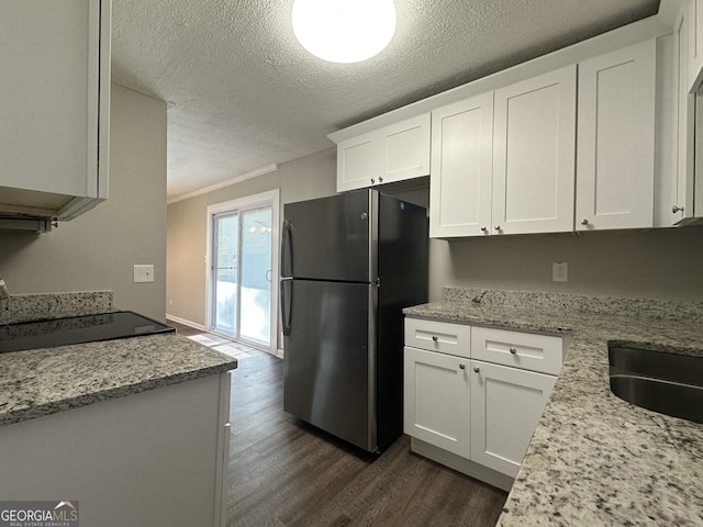 kitchen featuring light stone counters, crown molding, white cabinets, dark hardwood / wood-style floors, and stainless steel refrigerator