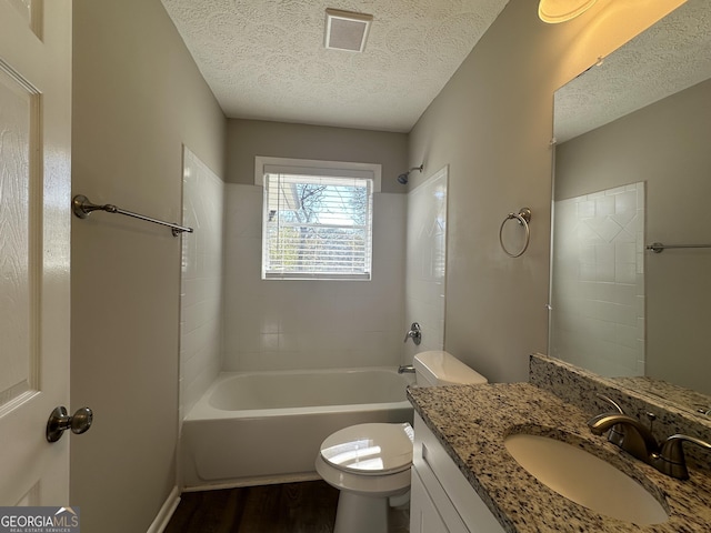 full bathroom with vanity, a textured ceiling, tiled shower / bath combo, hardwood / wood-style flooring, and toilet