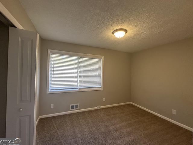 carpeted empty room with a textured ceiling