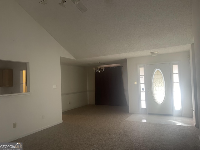 carpeted entrance foyer with a textured ceiling, vaulted ceiling, and a notable chandelier