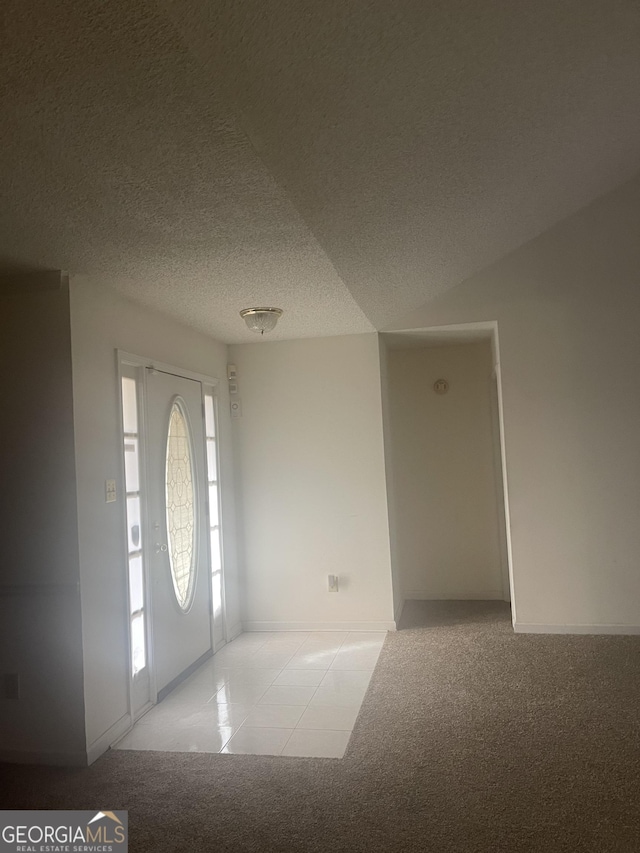 carpeted foyer featuring a textured ceiling