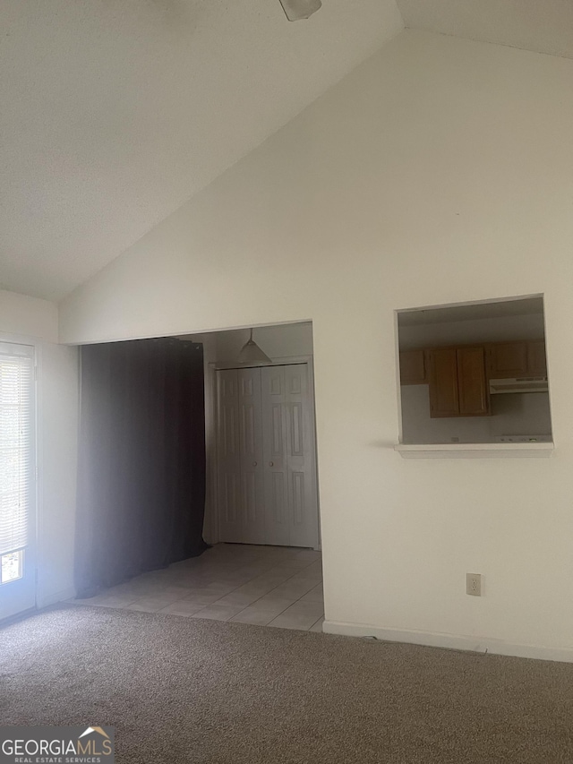 carpeted empty room featuring vaulted ceiling