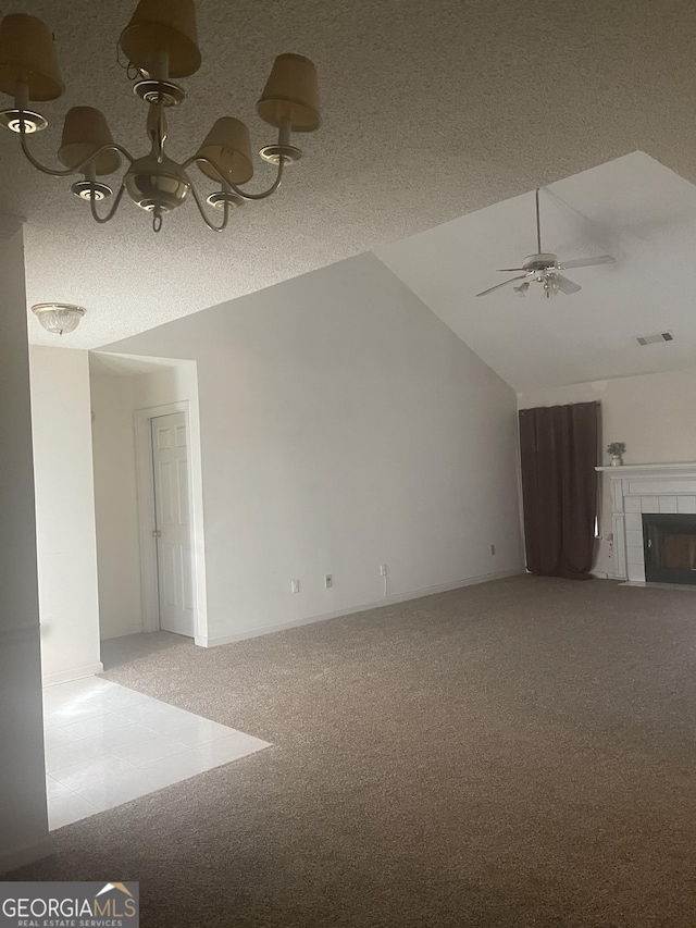 unfurnished living room with a textured ceiling, vaulted ceiling, ceiling fan, carpet floors, and a tiled fireplace