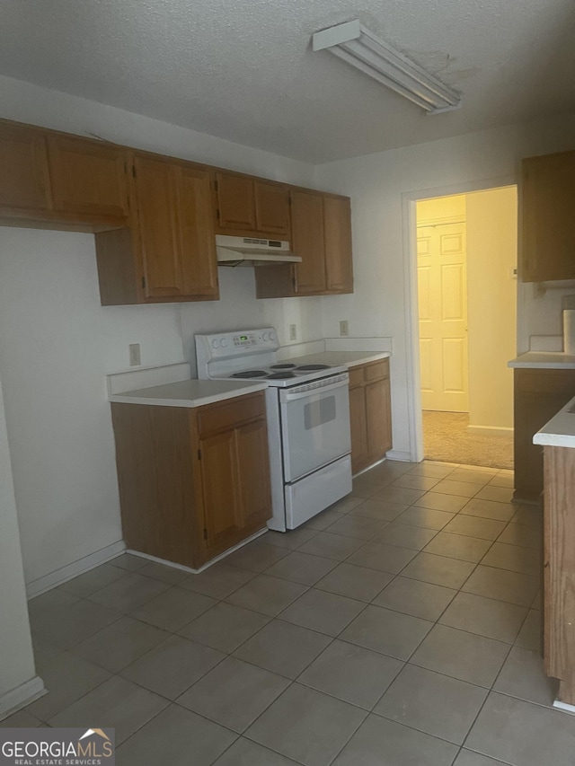 kitchen featuring white range with electric cooktop, light tile patterned floors, and a textured ceiling