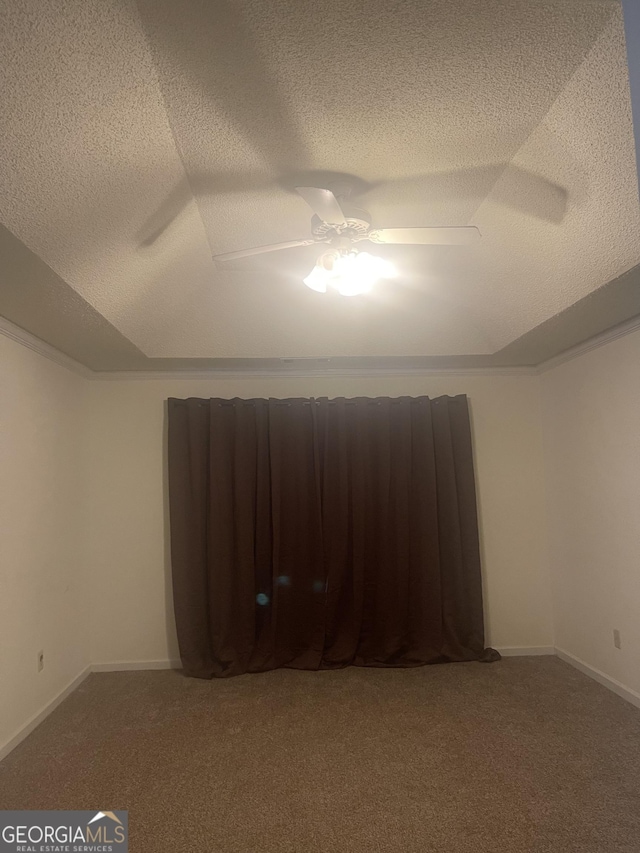 carpeted empty room with a textured ceiling, a tray ceiling, and ceiling fan