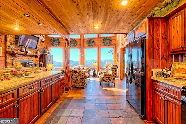 kitchen with hardwood / wood-style flooring, wooden walls, light stone countertops, and black refrigerator with ice dispenser