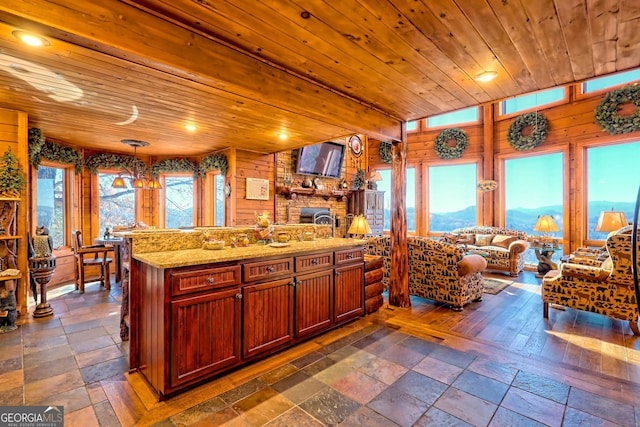 kitchen featuring pendant lighting, wood ceiling, a healthy amount of sunlight, and wood walls