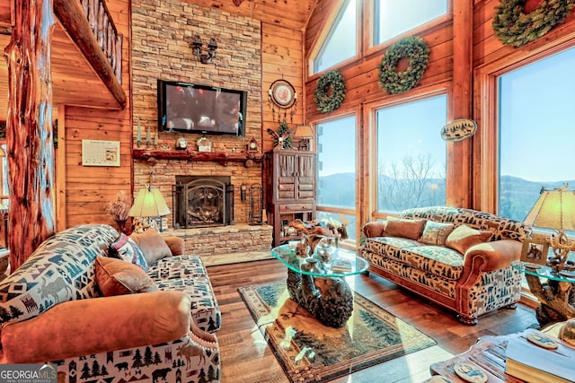 living room with a fireplace, hardwood / wood-style flooring, high vaulted ceiling, and wood walls