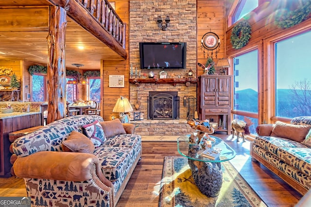 living room featuring a fireplace, wooden walls, plenty of natural light, and wood-type flooring