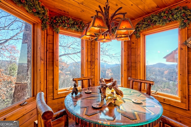 dining room featuring a mountain view, a healthy amount of sunlight, and wooden ceiling