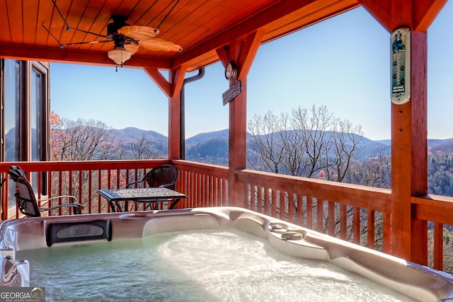 wooden deck featuring a mountain view, ceiling fan, and a hot tub