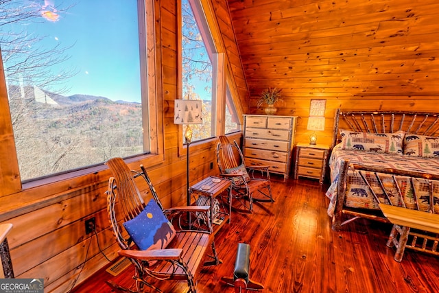 bedroom featuring hardwood / wood-style flooring, a mountain view, lofted ceiling, and wooden walls