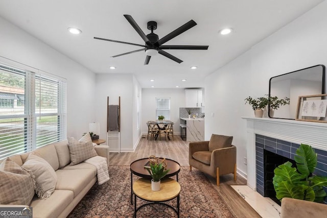 living room with a fireplace, light hardwood / wood-style floors, and ceiling fan