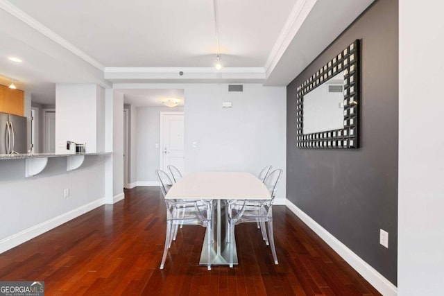 unfurnished dining area featuring dark hardwood / wood-style floors, crown molding, and a tray ceiling