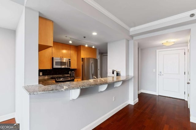 kitchen with stone counters, dark wood-type flooring, kitchen peninsula, a breakfast bar, and appliances with stainless steel finishes