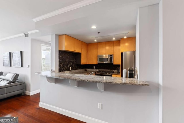 kitchen with kitchen peninsula, dark wood-type flooring, stone countertops, and appliances with stainless steel finishes