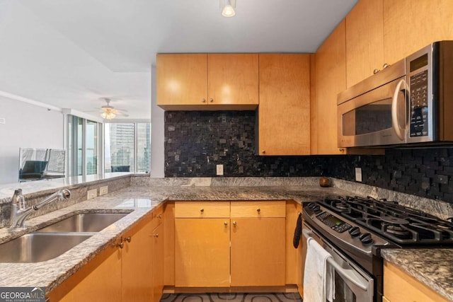 kitchen with light stone countertops, sink, ceiling fan, and stainless steel appliances