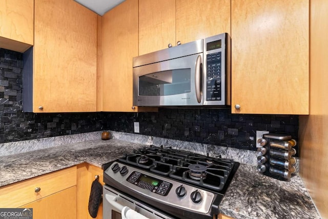 kitchen featuring backsplash, appliances with stainless steel finishes, and dark stone counters