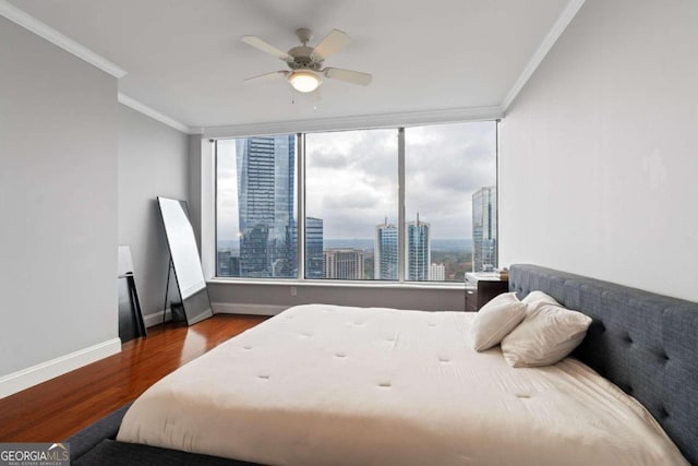 bedroom featuring ceiling fan, wood-type flooring, ornamental molding, and multiple windows