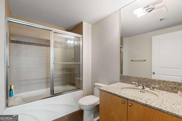 full bathroom with tile patterned floors, vanity, enclosed tub / shower combo, and toilet