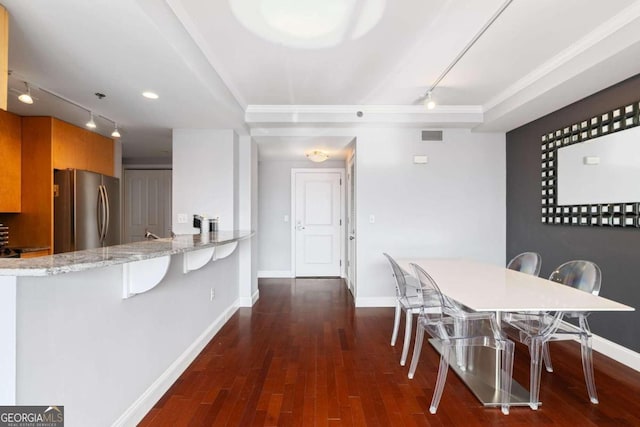 dining space featuring dark wood-type flooring, a tray ceiling, and track lighting