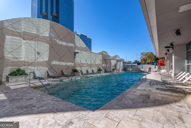 view of swimming pool with pool water feature and a patio area