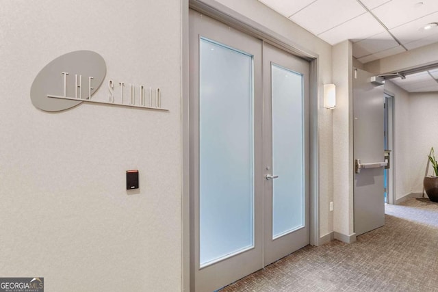 hallway with french doors, carpet floors, and a drop ceiling