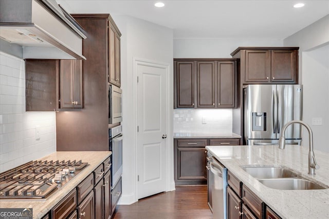 kitchen featuring sink, dark wood-type flooring, appliances with stainless steel finishes, light stone counters, and custom exhaust hood