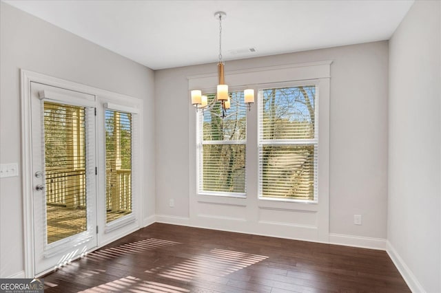 unfurnished dining area with an inviting chandelier and dark hardwood / wood-style flooring