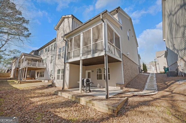 back of property with a sunroom, central AC unit, and a patio area